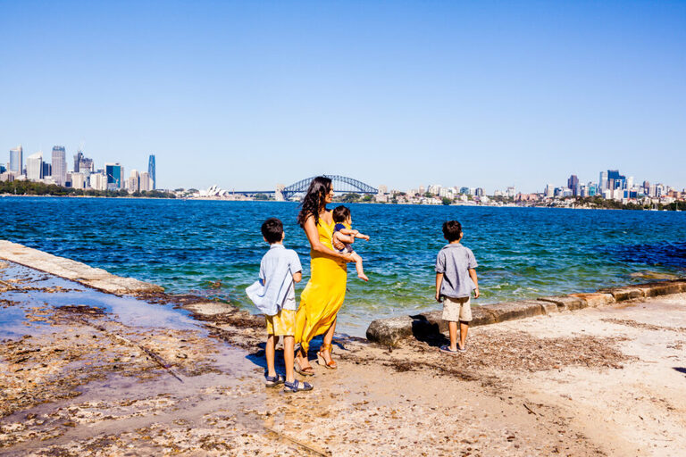 A mother and her three boys stand looking out to the harbour while the wind blows their clothes 