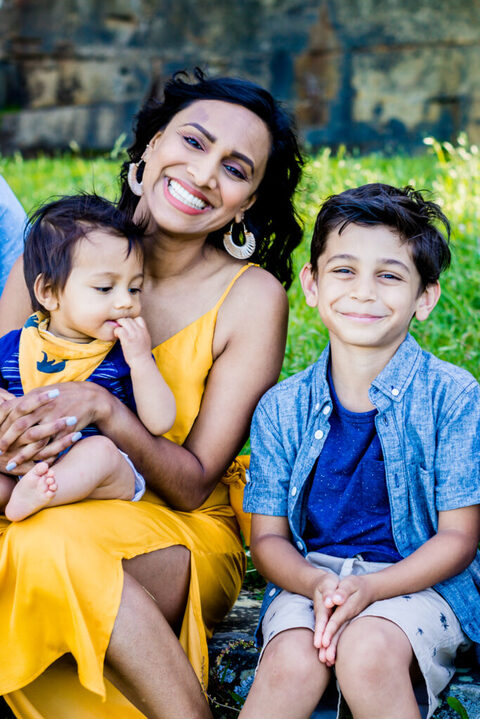 A mother and her two children smiling and wearing blue and yellow clothes