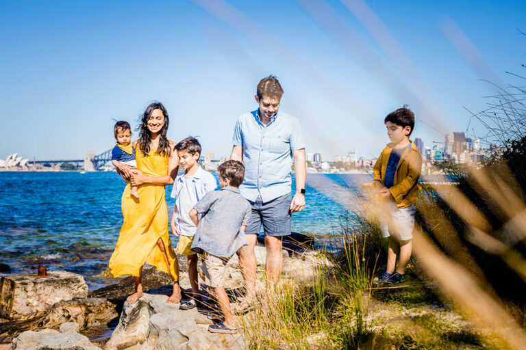 A family dressed in blue and yellow standing on some rocks overlooking Sydney Harbour
